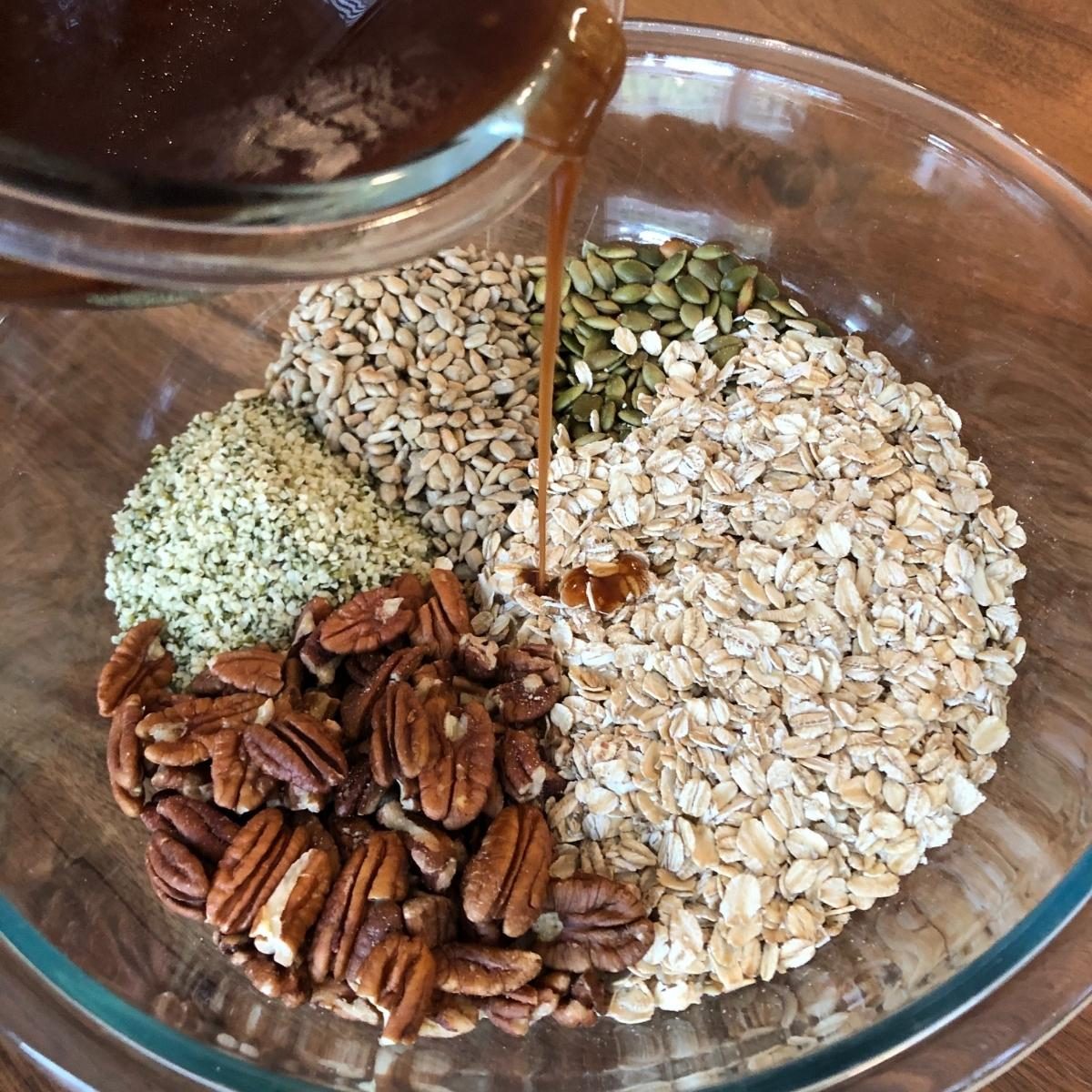 pouring maple syrup over dry hemp granola ingredients. 