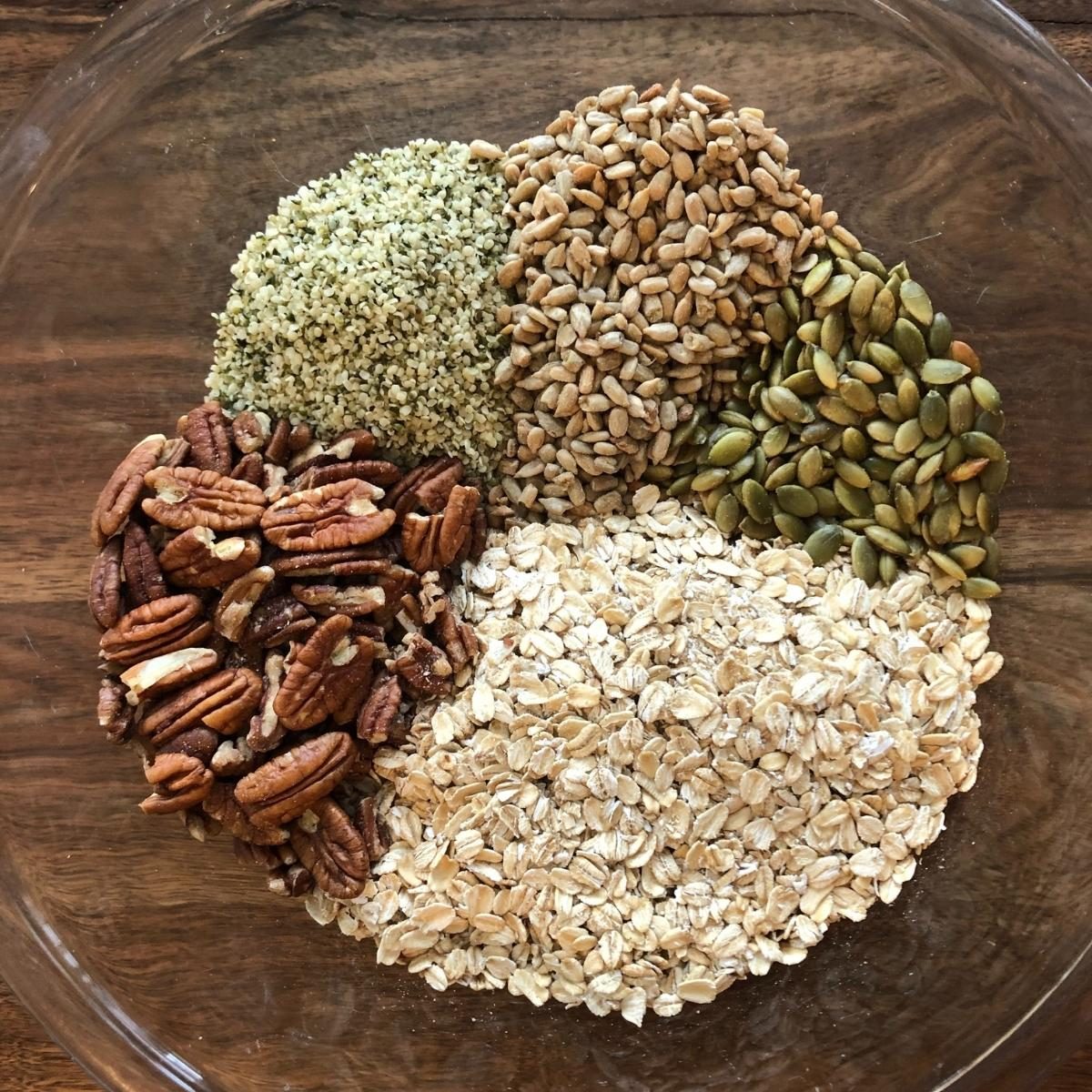 bowl with hemp seed granola ingredients, oats, pecans, seeds, hemp hearts.