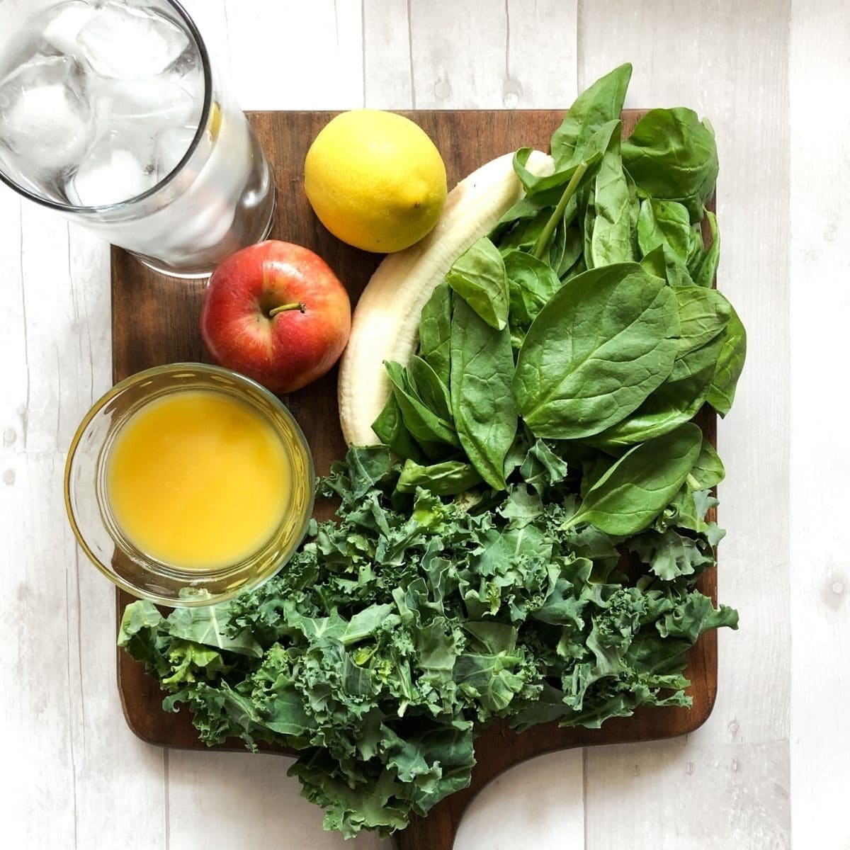 smoothie ingredients on a white background, kale, spinach, banana, lemon, apple, water, orange juice. 