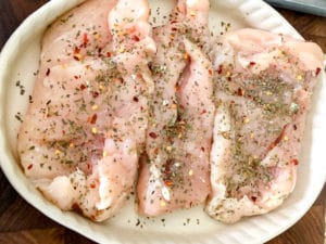 Raw chicken breast with Italian spices ready to be pan seared for Italian Chicken with Tomatoes and Fresh Mozzarella