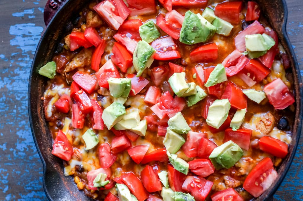 Chicken Burrito Skillet Dinner with melted cheese and topped with fresh tomatoes and avocados.