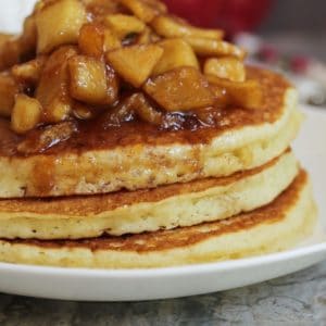 Caramelized apples on top of a stack of fluffy pancakes