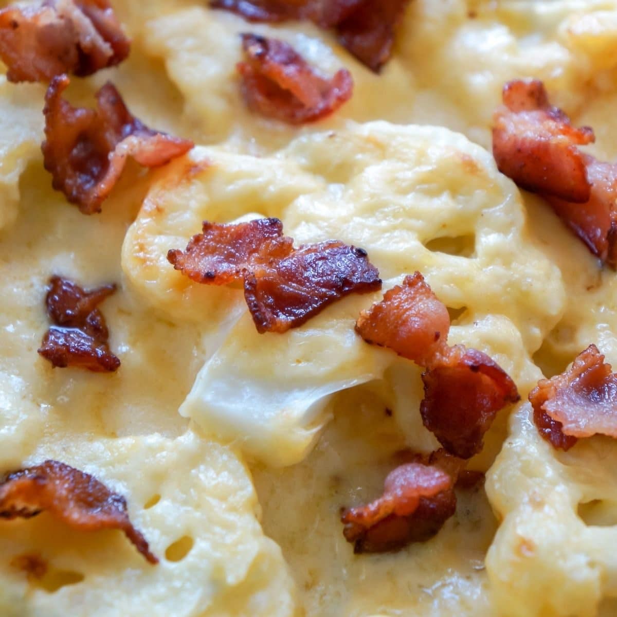 Close up photo of cheesy baked cauliflower casserole topped with bacon.