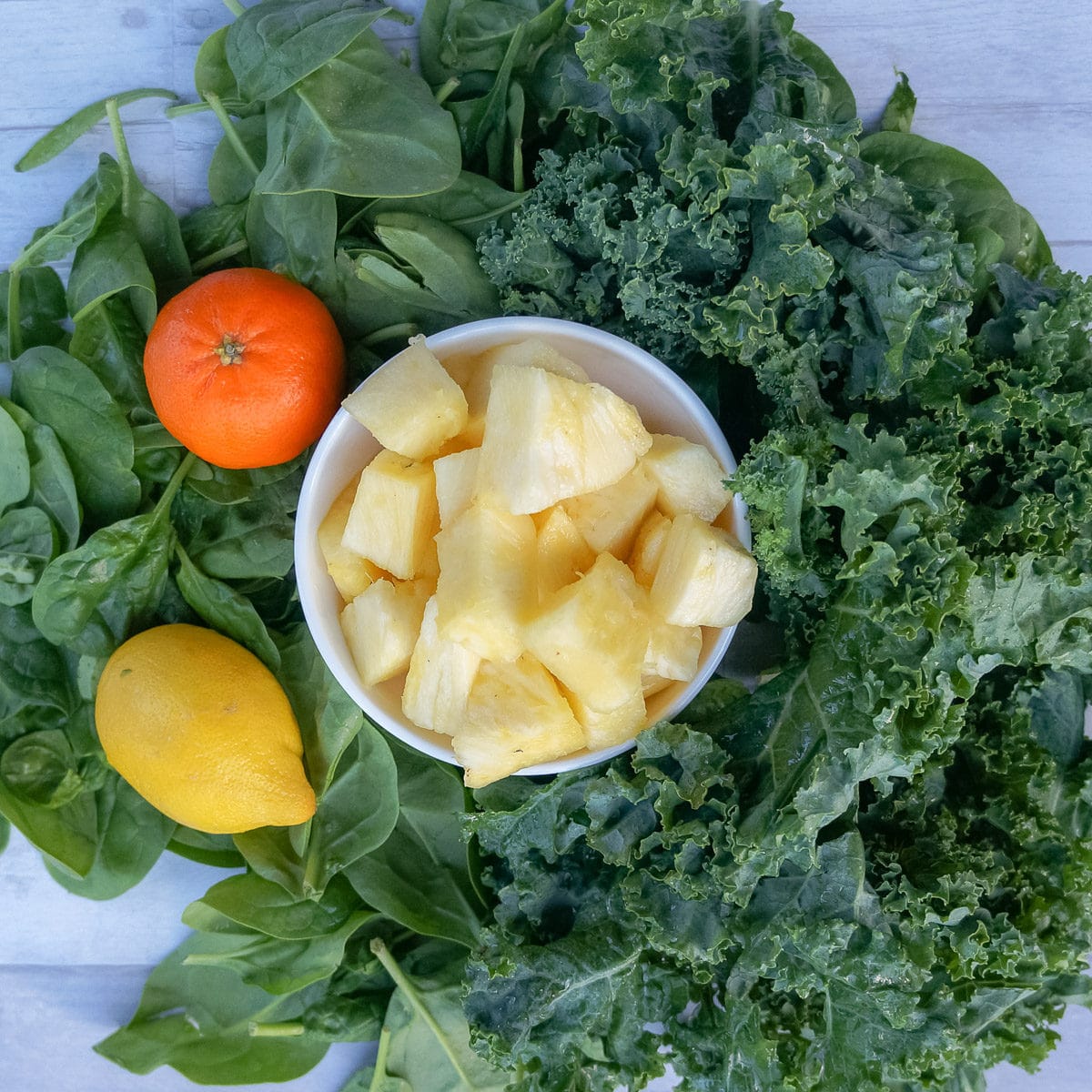 Iron rich smoothie ingredients - kale, spinach, lemon, pineapple, orange
