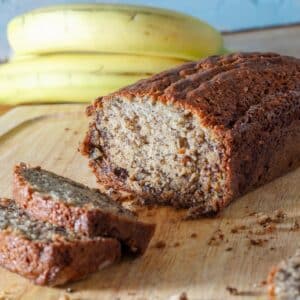 loaf of oat flour banana bread with bananas in the background