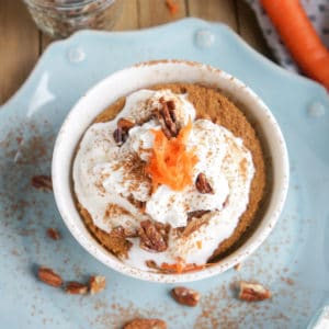 Carrot Cake in a mug topped with whipped cream, cinnamon, pecans, and carrots.