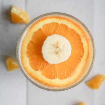 Bright orange smoothie with sliced orange and banana on top