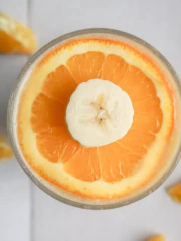 Bright orange smoothie with sliced orange and banana on top