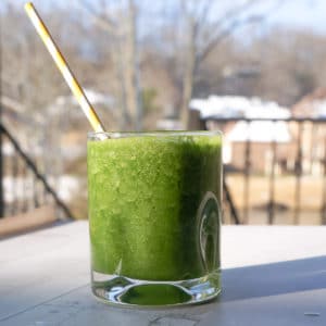 Green smoothie in a glass with a yellow straw
