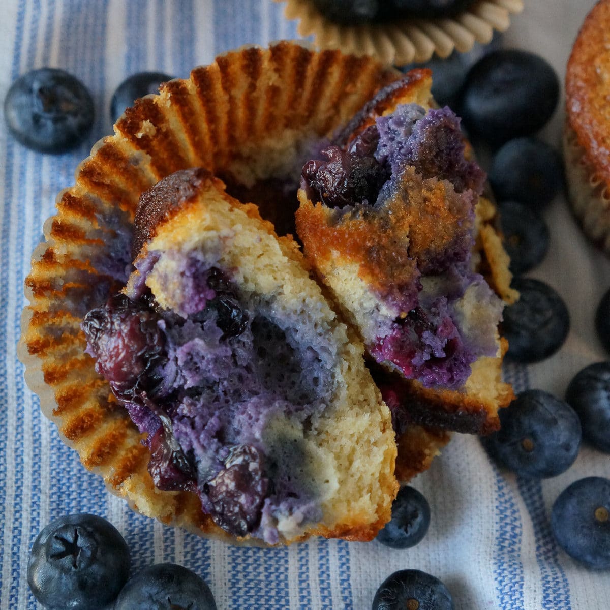 blueberry muffins on a table with fresh blueberries and a cup of coffee