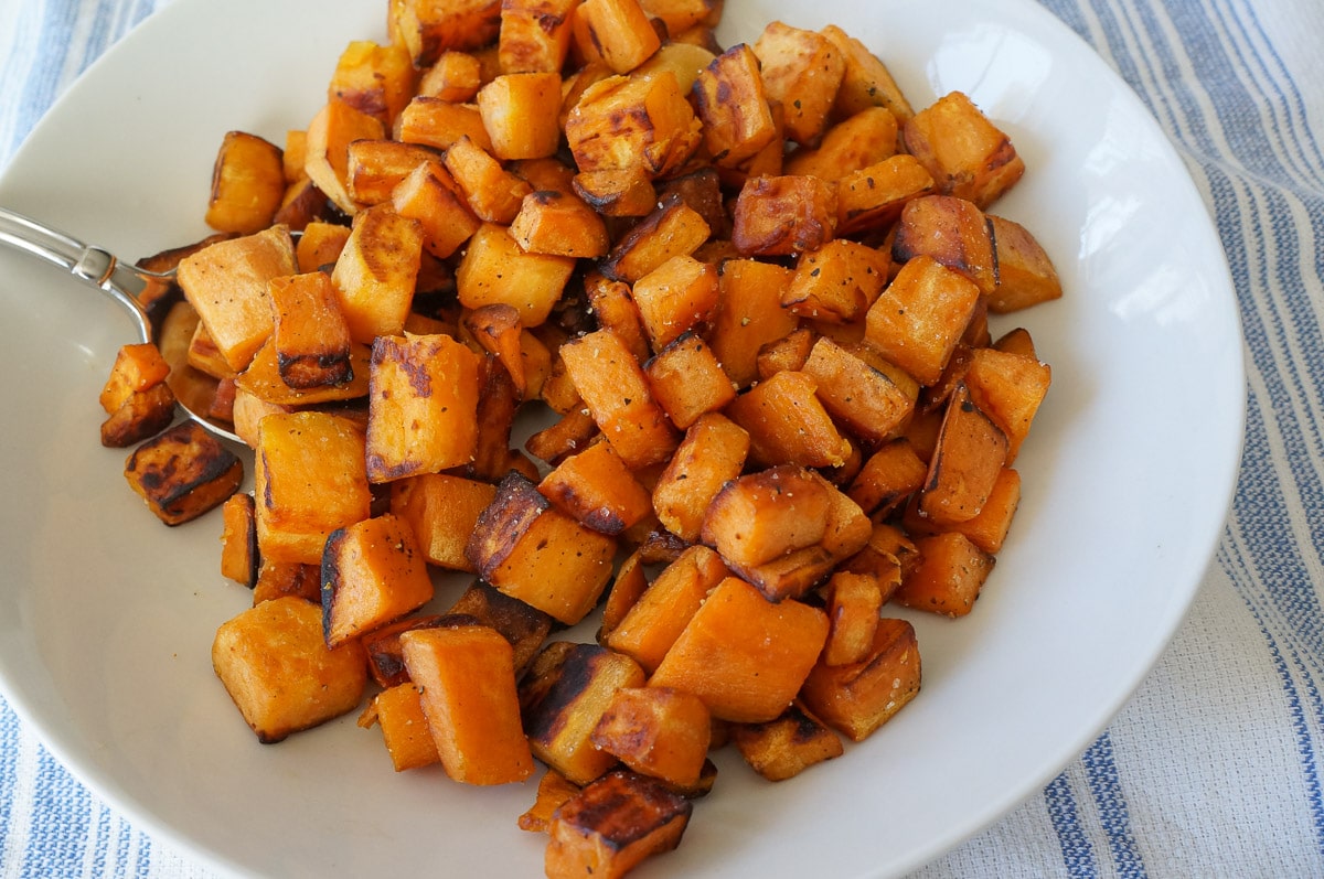 cubbed and sautéed sweet potatoes in a white bowl. 