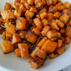 cooked cubbed sweet potatoes in a white dish.