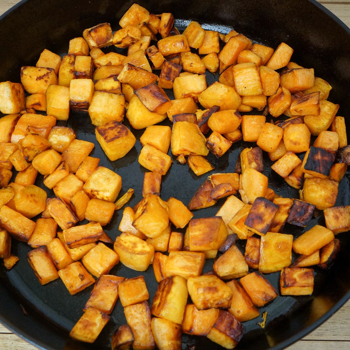 Cubed pan-seared sweet potatoes in a large cast iron pan.