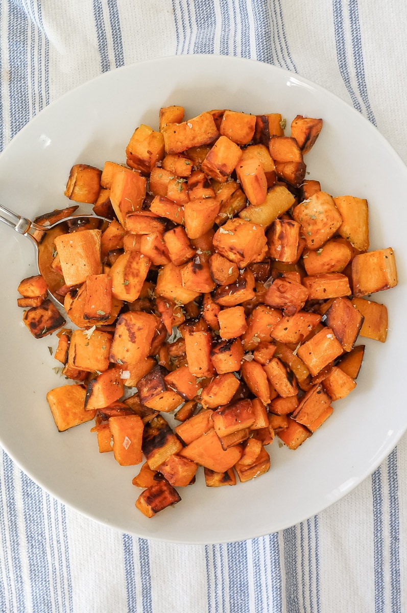 cubbed cooked sweet potatoes in a white bowl, background is white with a light blue stripe