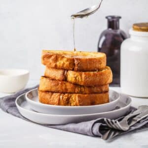 stack of fluffy protein French Toast being drizzled with maple syrup